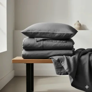 A charcoal grey linen duvet cover set with matching pillowcases neatly folded on a wooden bench.