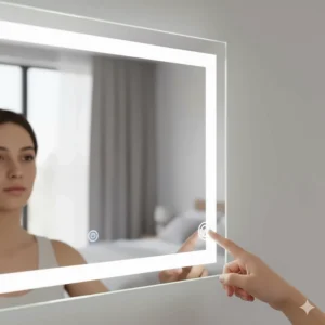 A hand interacting with a touch-sensitive power button on the glass of a lit vanity mirror to adjust brightness levels.