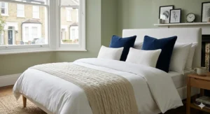 Two large navy blue velvet cushions styled on a bed with white linen for a boutique hotel look.