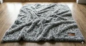 Overhead view of a thick, ruffled faux fur throw in shades of silver and slate grey.