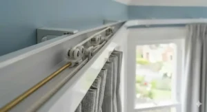 High-resolution close-up showing the intricate internal moving parts, roller gliders, and pulley system of a premium corded white aluminium curtain track mounted in a domestic bay window.