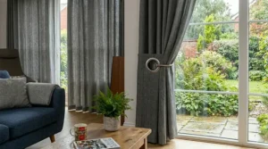 Heavyweight thermal eyelet curtains in a soft cream fabric, closed to retain heat in a British bedroom.