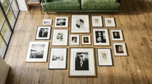 A high-resolution flat-lay of the gallery wall frames set components, displaying the specific mixture of thin black, natural oak wood, and ornate gold finishes with white matting, laid out on a light wooden floor.