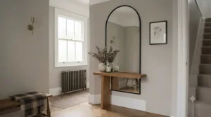 Modern black metal arched mirror hanging in a contemporary British hallway.