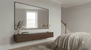 Sleek, minimalist large wall mirror with a thin black frame positioned in a modern bedroom.